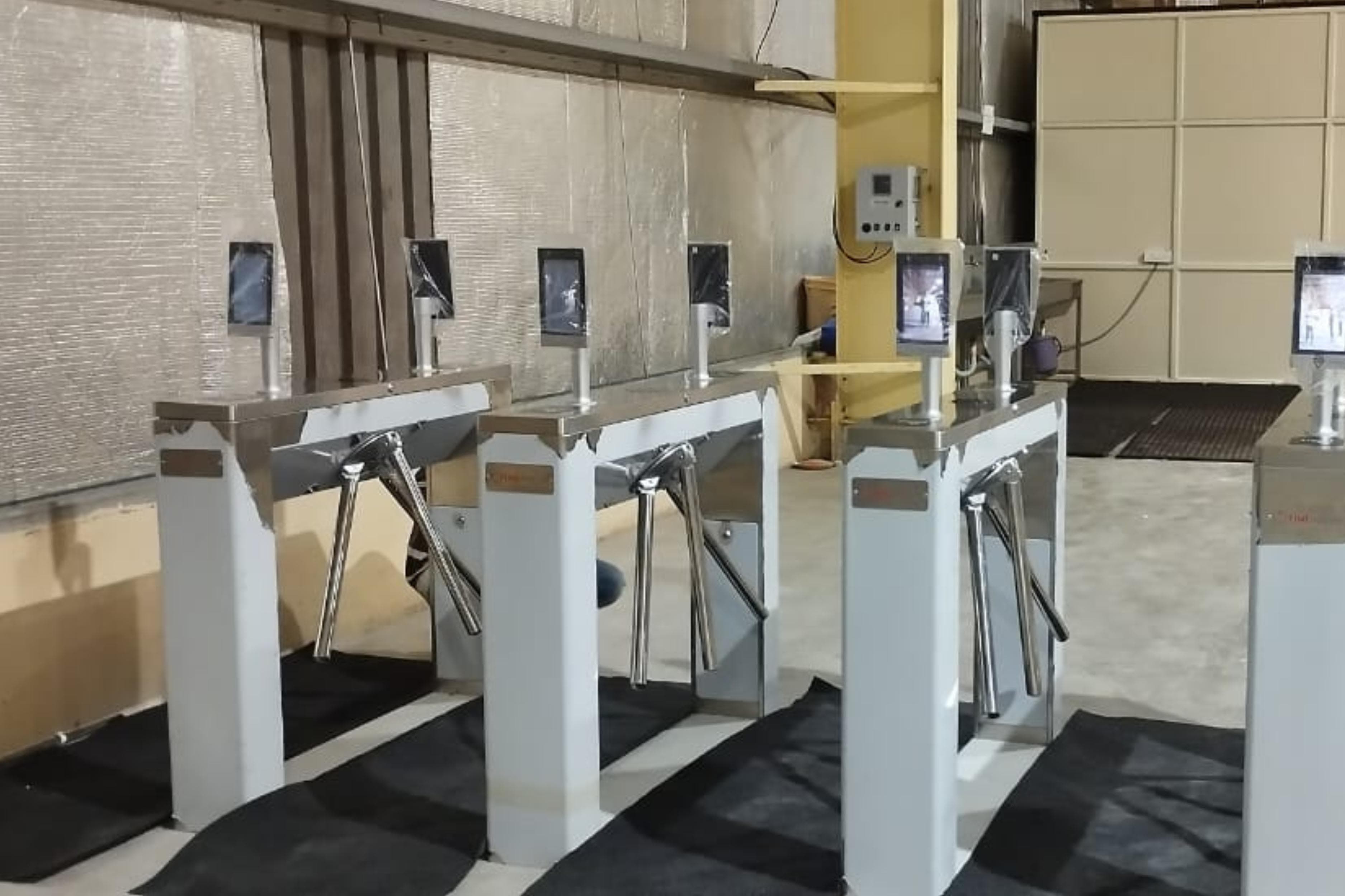 Row of tripod turnstile lanes with face recognition terminals at an industrial site entrance